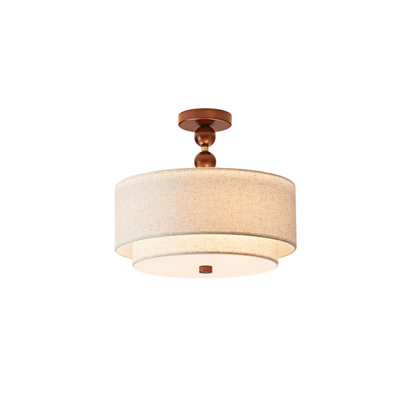 Clérachic walnut and linen double-drum light, a wooden ball stem above the lit linen shades, on a white background.