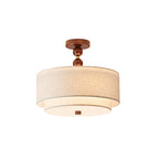Clérachic flush-mount light in walnut and linen, lit, with a round white diffuser under its two linen tiers, on white.