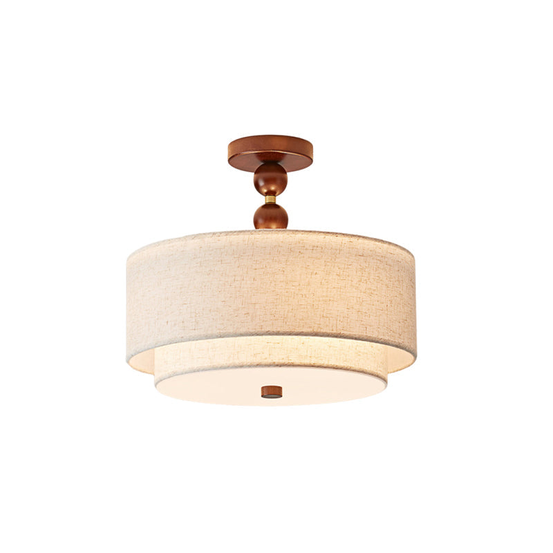 Clérachic flush-mount light in walnut and linen, lit, with a round white diffuser under its two linen tiers, on white.