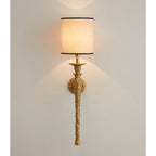 Beige shade with a black trim on this Clérachic wall light, lit and casting soft arcs of light up and down a grey-white wall.