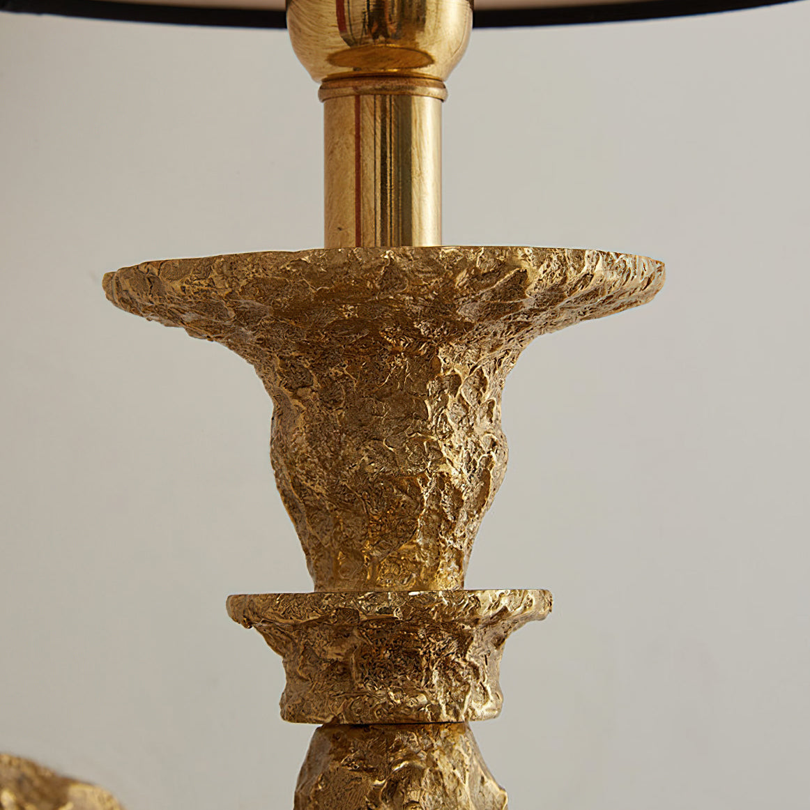 Close view of the hammered antique brass collars and neck below the shade on this Clérachic wall light.