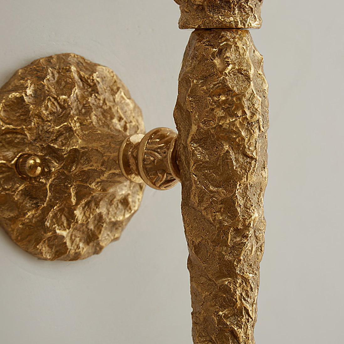 Close view of the hammered brass stem meeting the wall plate on this Clérachic wall light.