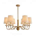 Lit gold Clérachic chandelier with six linen shades, a ceiling canopy and a straight rod, shown on a white backdrop.