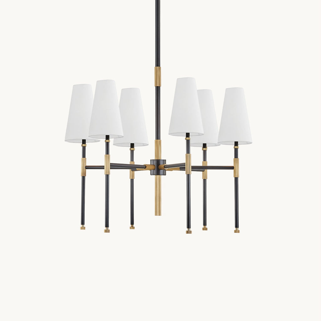 This Clérachic six-light chandelier on a plain off-white backdrop, with six white linen shades on black arms with brass joints.