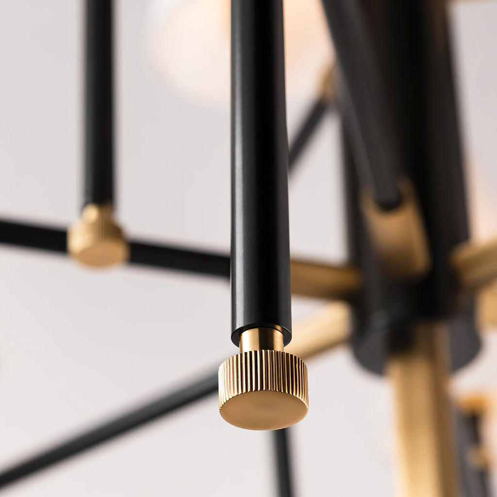 Close view of a fluted brass knob on the end of a black arm on this Clérachic chandelier, with a soft white shade out of focus behind.