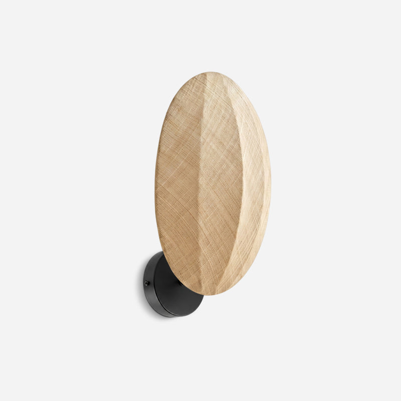 Clérachic wall light on a pale grey backdrop, a tall linen oval shade with a woven texture on a round black wall plate.
