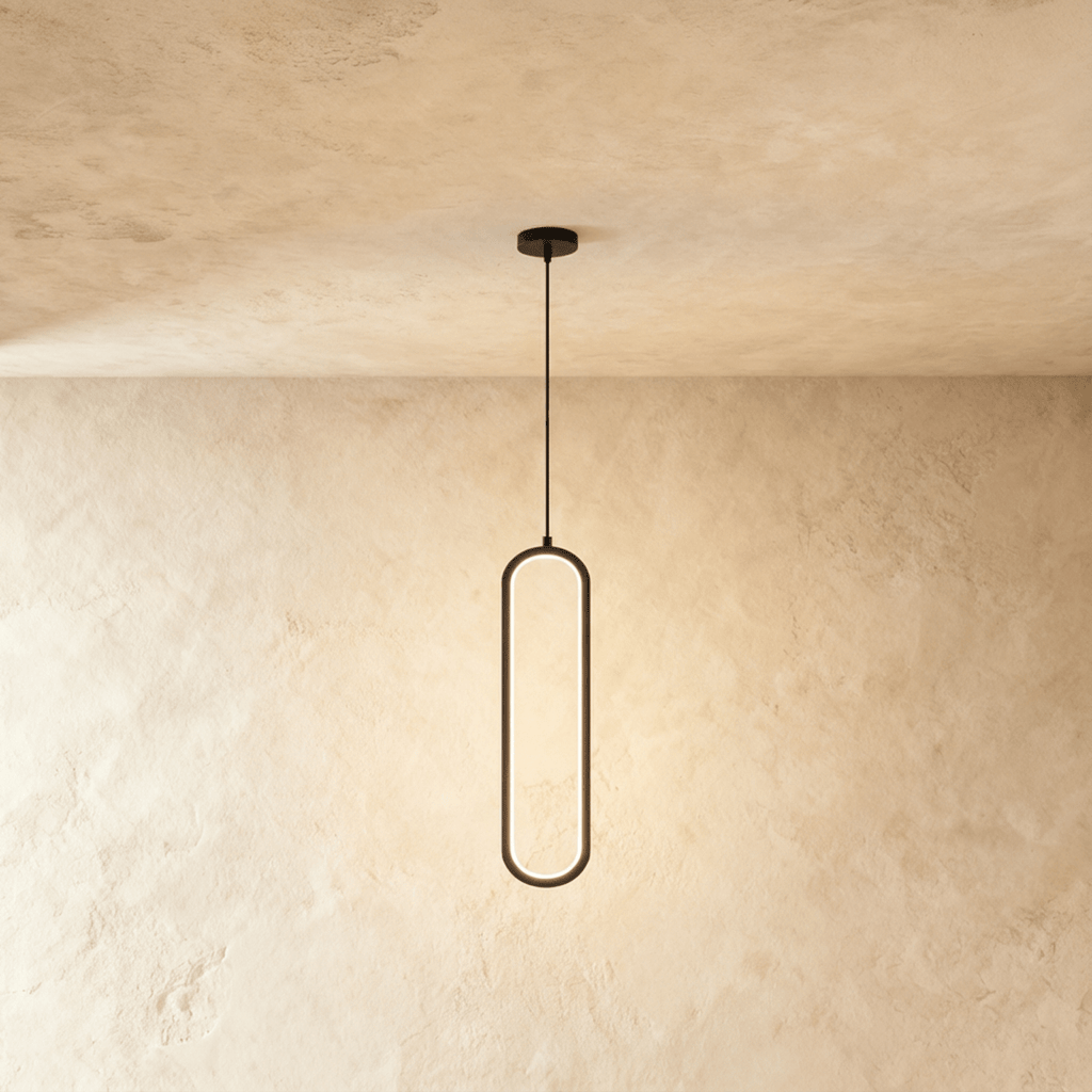 Clérachic slim black oval LED loop pendant, its inner edge glowing warm, hung from a cord on a limewashed wall.