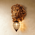 Clérachic gold resin lion head wall light with a caged crystal lantern glowing warmly against a limewashed plaster wall.