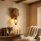 Clérachic gold lion head wall light with crystal lantern above a rustic shelf with books and candles beside an armchair.