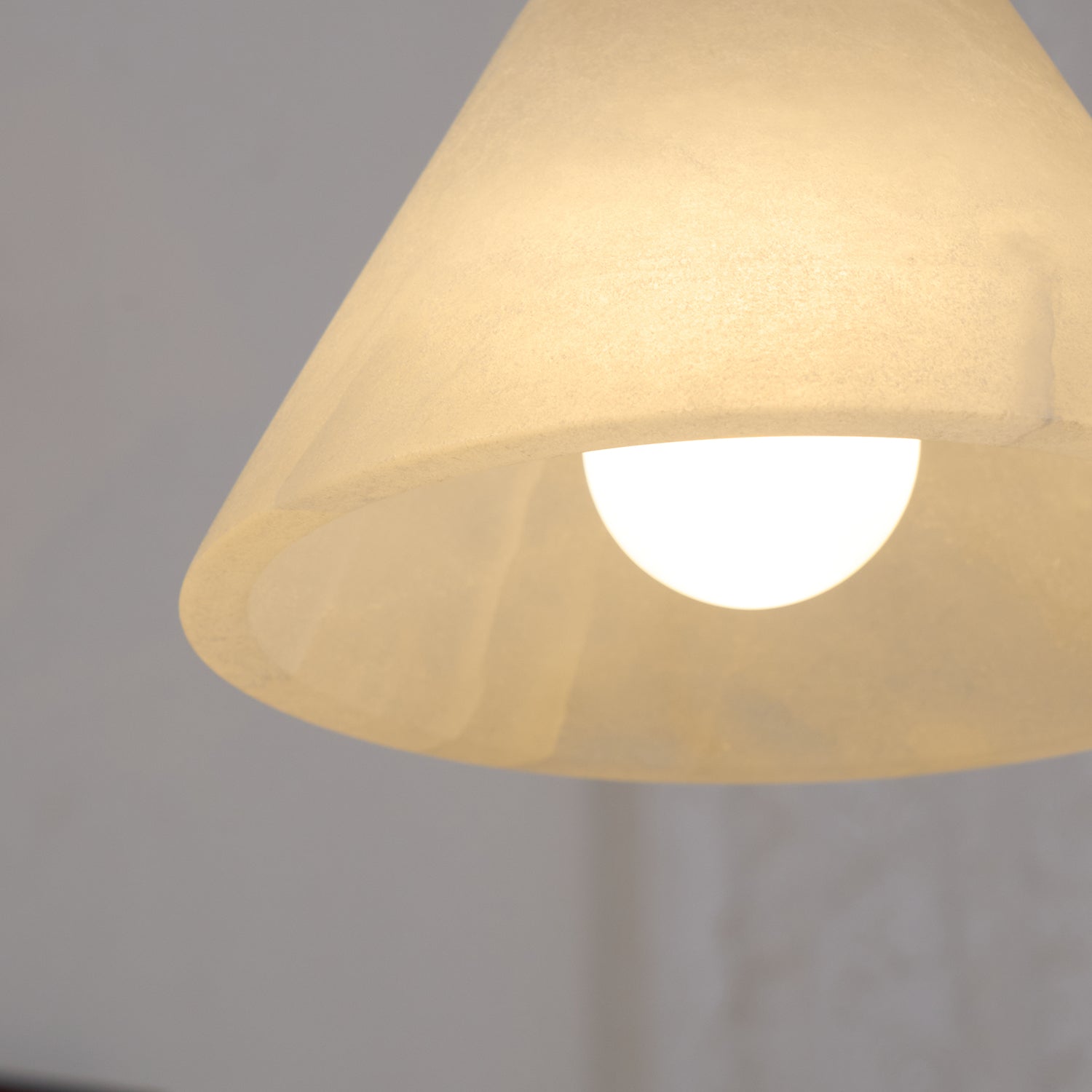 Clérachic pendant seen from below, the lit shade showing the rounded opal lamp tucked inside its rim.