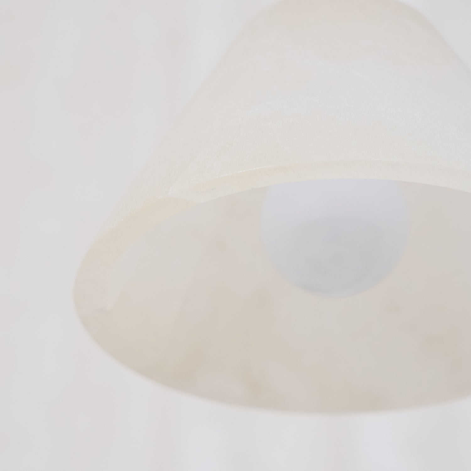 Clérachic shade photographed softly from underneath, the lamp a pale disc within the cone's open mouth.
