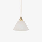 The Clérachic conical shade unlit on white, cool and chalky, hung from a slim brushed brass fitting.