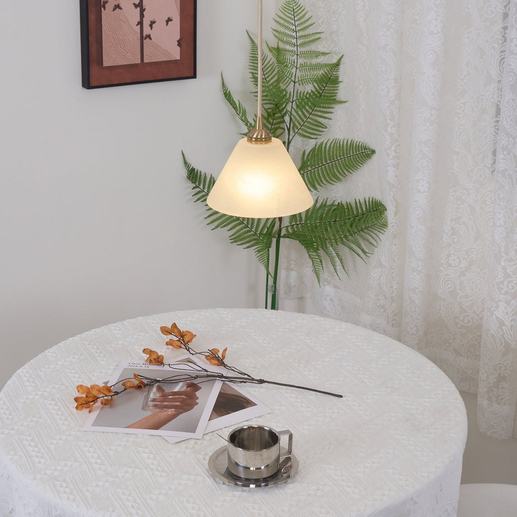 The Clérachic light lit above a round lace-covered table with a fern and framed print in a bright corner.