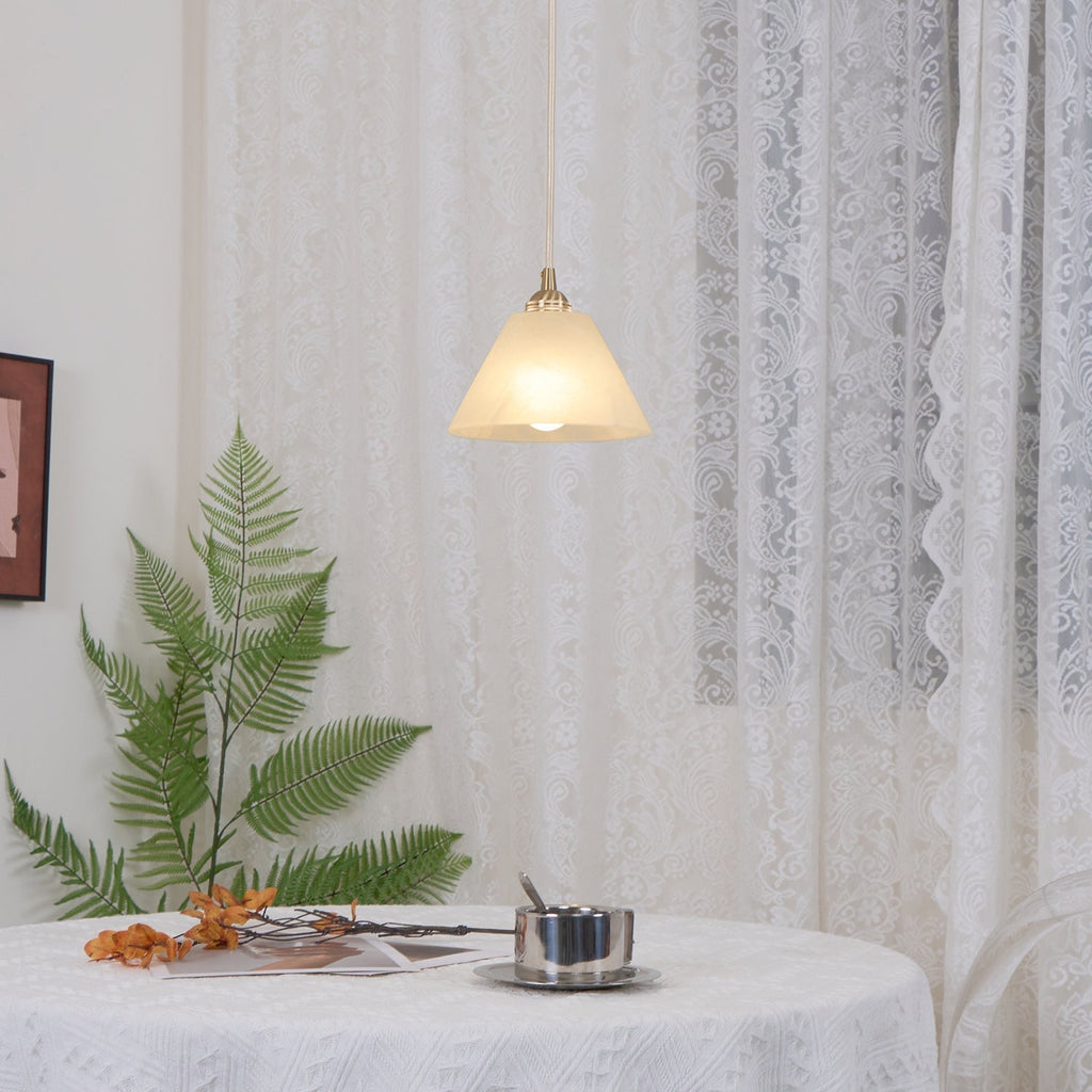 The Clérachic cone hung low over a styled tabletop, its shade warm against pale lace drapery.