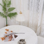 Clérachic pendant framed close in the room, the lit cone reading amber with fern fronds behind it.