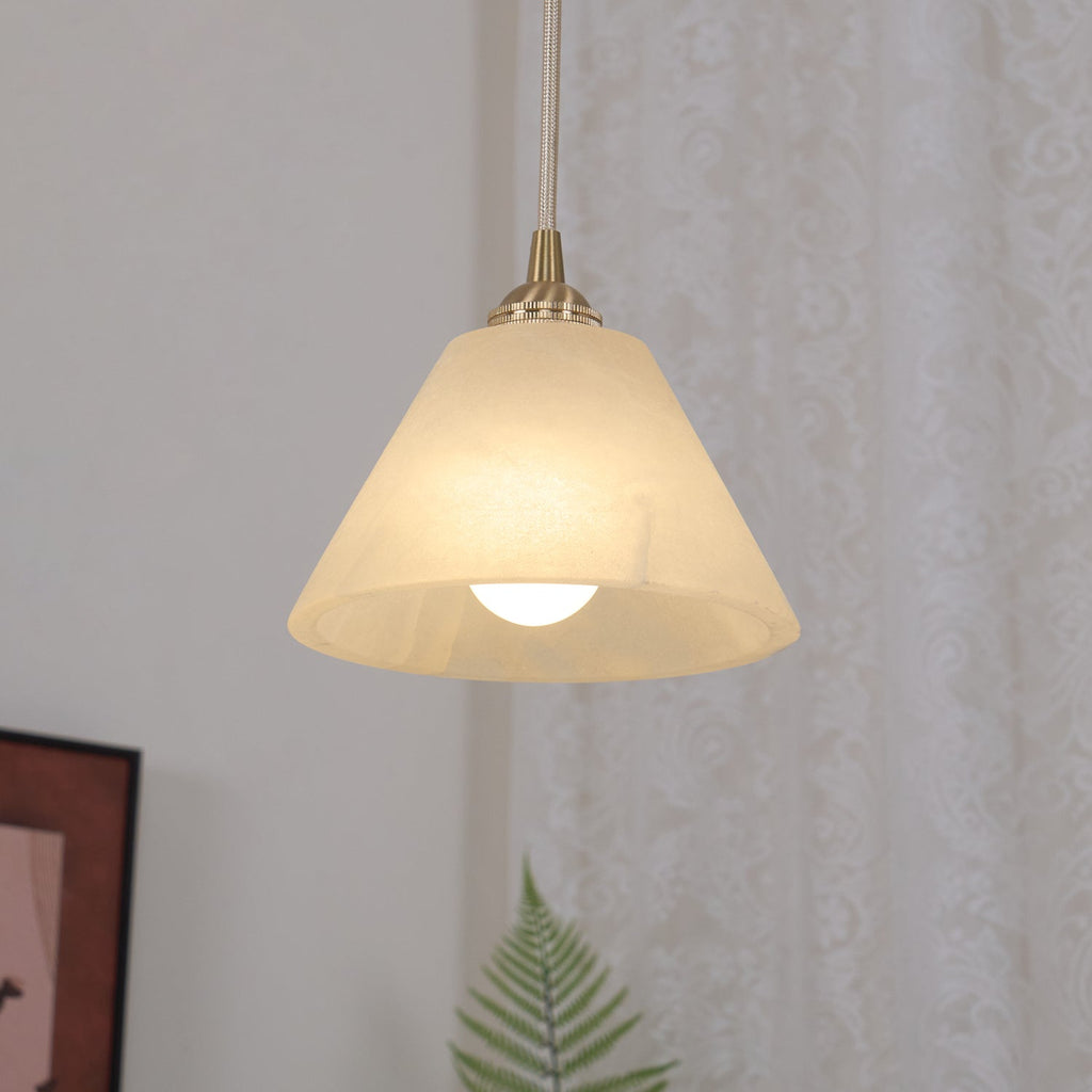 The Clérachic shade lit warm against a curtained wall, its cone silhouette clean above the framed art.