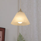The Clérachic shade lit warm against a curtained wall, its cone silhouette clean above the framed art.