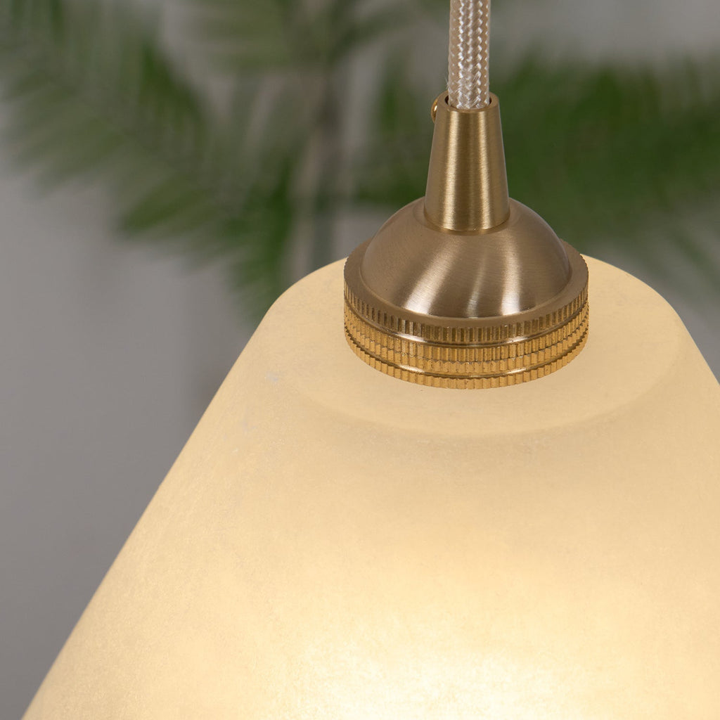 Clérachic brass collar shown in macro, its knurled ring seated on the glowing alabaster shade.