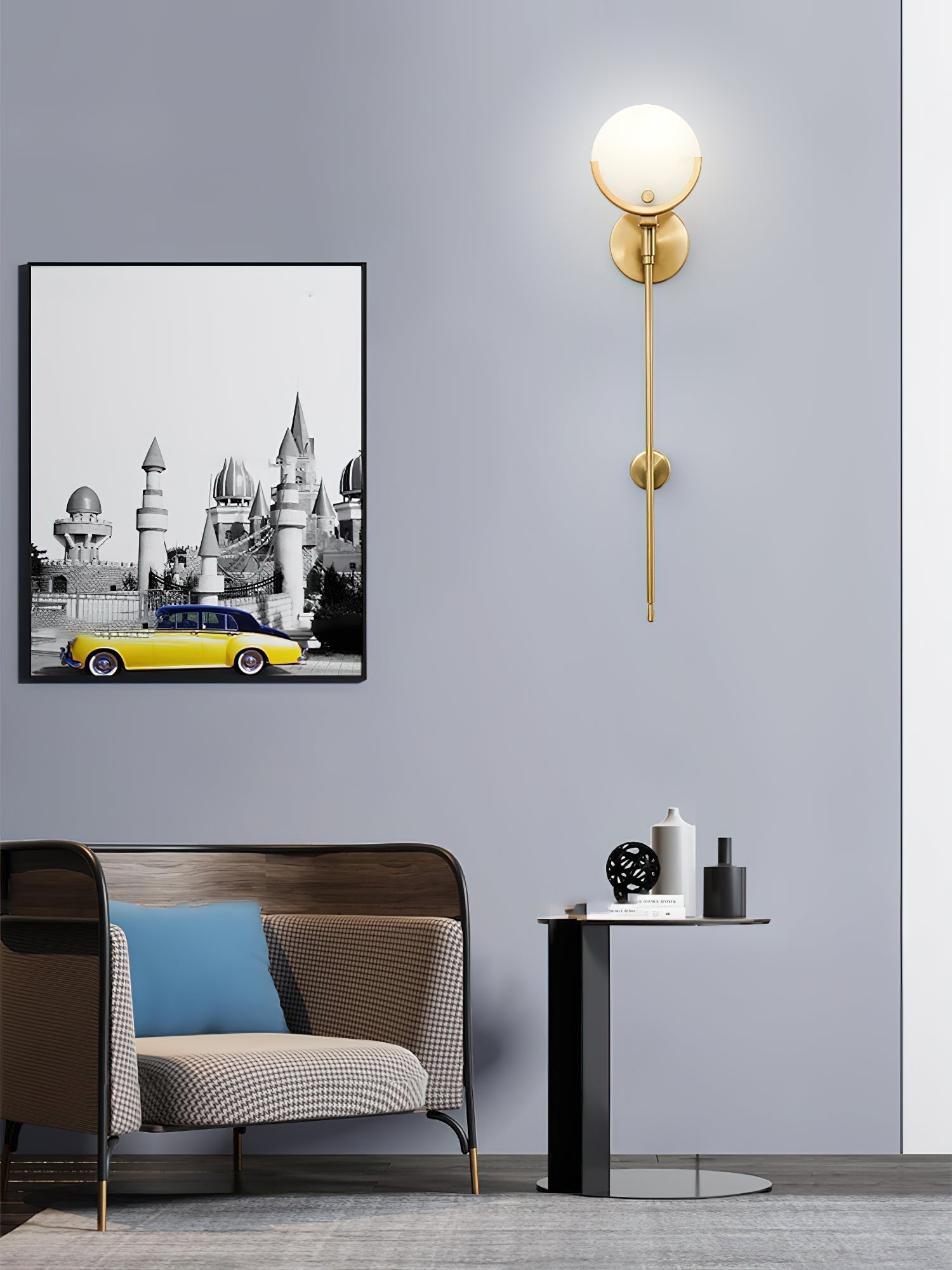 The Clérachic sconce lighting a pale grey wall in a sitting room, the alabaster disc glowing above its tapered brass stem.