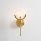 Clérachic sconce lit softly head-on, warm light bringing out the cloudy grey veining across the alabaster disc.