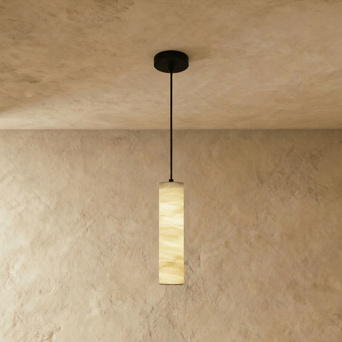 Clérachic taller alabaster cylinder pendant hung from a black cord and canopy, golden veining glowing on a plaster wall.