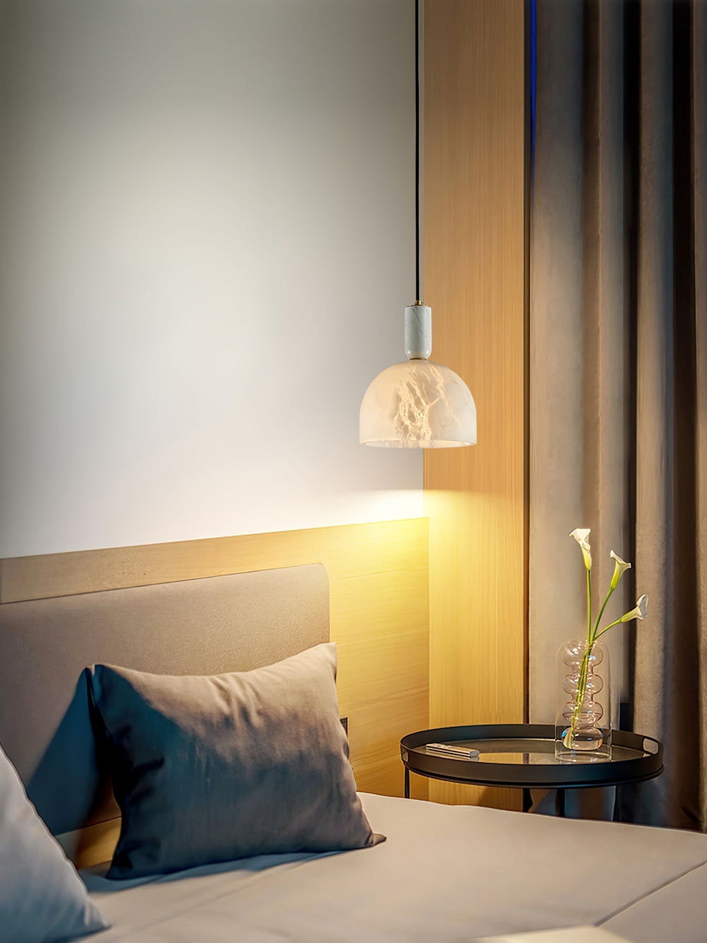 Clérachic Long-Drop Dome pendant light beside a bed, warm light spilling down a wood panel onto the bedside table.