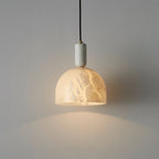 Clérachic Long-Drop Dome pendant light lit on a pale wall, honey veining clouding through the alabaster dome.