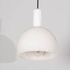 Close view of the Clérachic Long-Drop Dome pendant light, pale stone stem and brass ring above the carved dome.