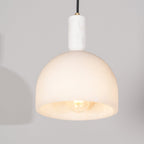 Clérachic Long-Drop Dome pendant light lit at close range, the bulb visible inside the open alabaster dome.