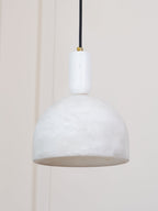 Unlit Clérachic Long-Drop Dome pendant light against a panelled cream wall, stone stem and small brass screw.