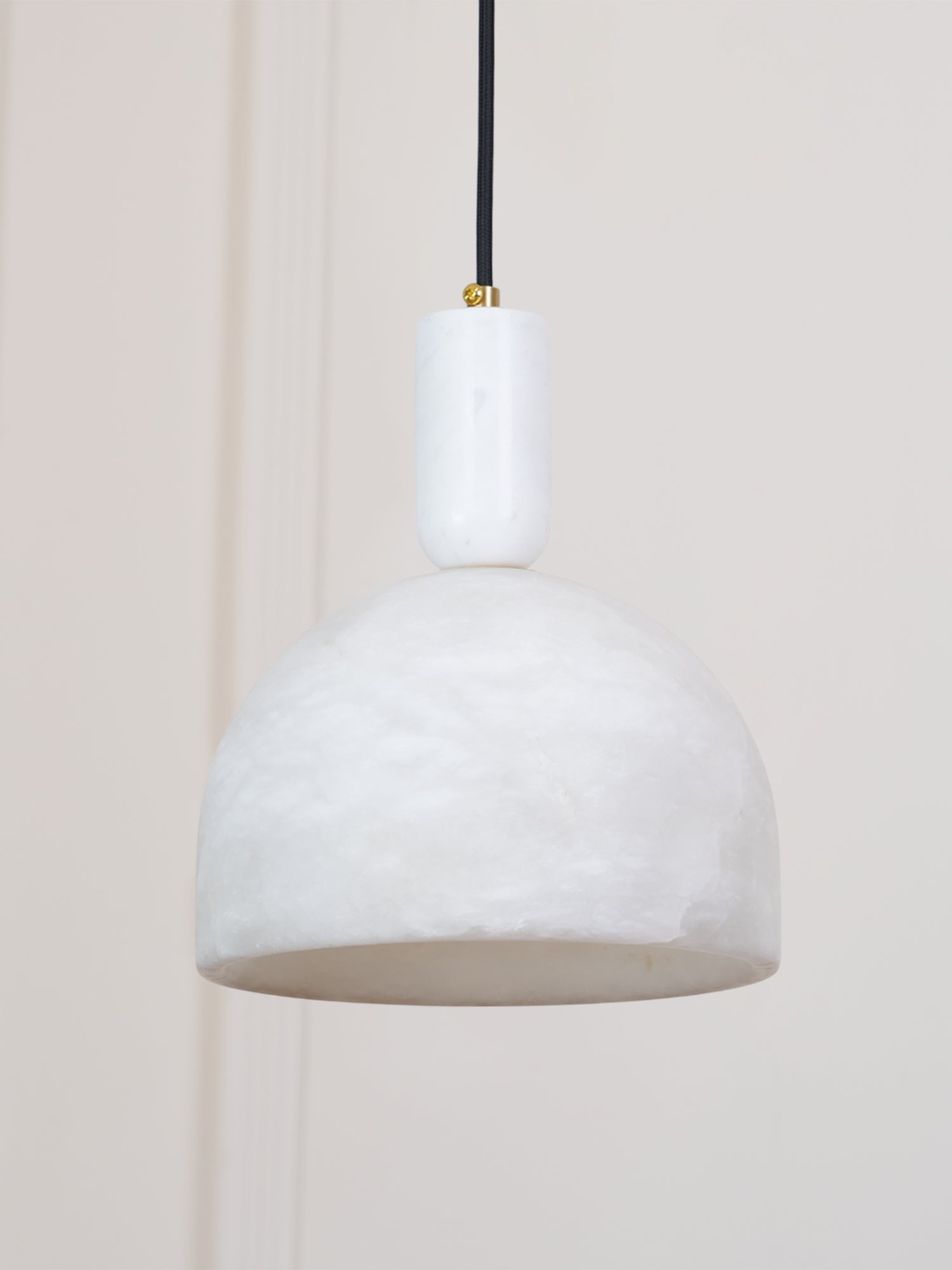 Unlit Clérachic Long-Drop Dome pendant light against a panelled cream wall, stone stem and small brass screw.