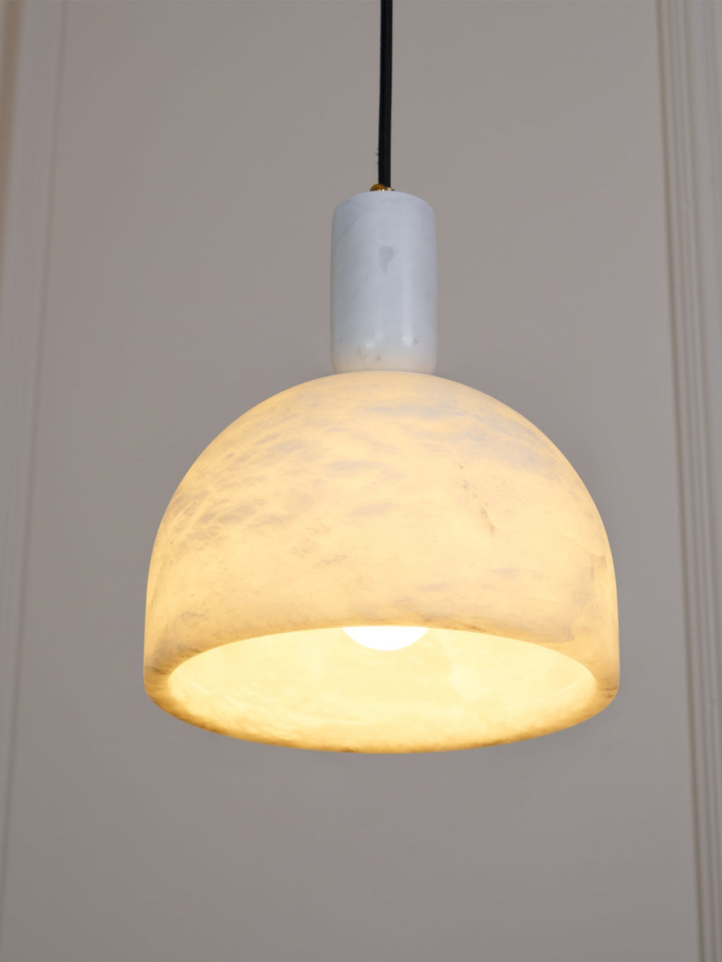 Clérachic Long-Drop Dome pendant light lit against panelling, the whole dome glowing and brightest at the rim.