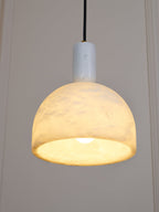 Clérachic Long-Drop Dome pendant light lit against panelling, the whole dome glowing and brightest at the rim.