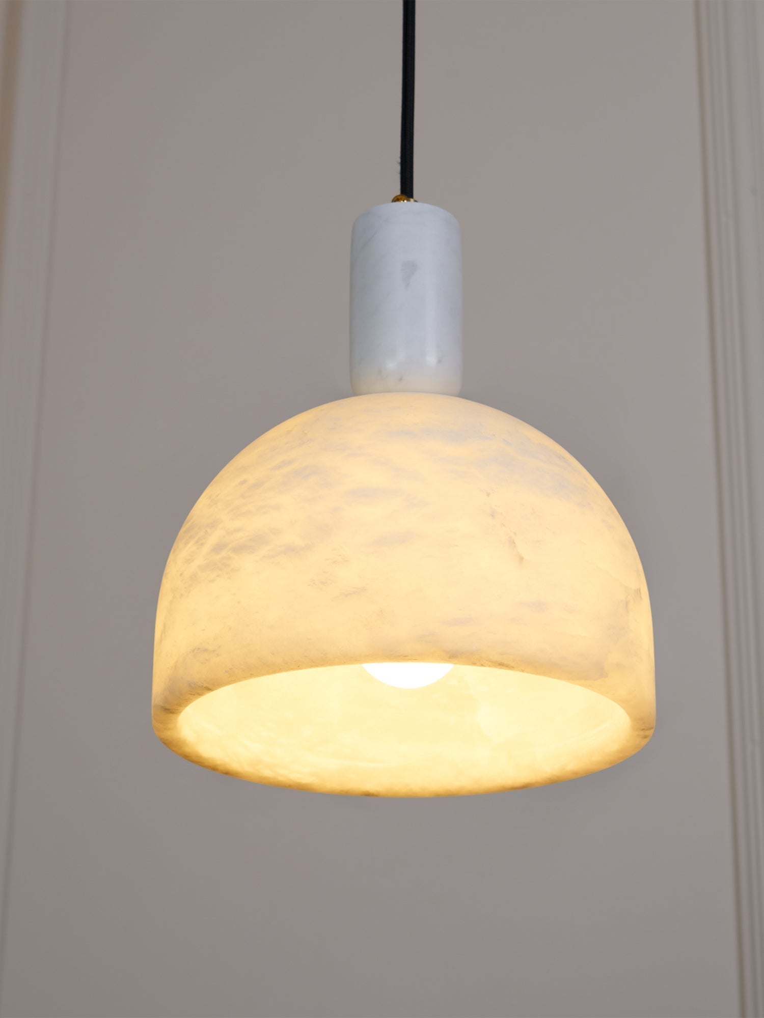 Clérachic Long-Drop Dome pendant light lit against panelling, the whole dome glowing and brightest at the rim.