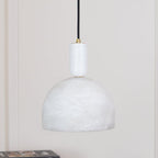 Unlit Clérachic Long-Drop Dome pendant light hanging in a quiet corner, pale stone against soft panelling.