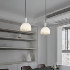 Two Clérachic Long-Drop Dome pendant lights lit over a table in a pale grey kitchen with open shelving.