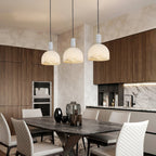 Three Clérachic Long-Drop Dome pendant lights above a stone dining table, wood cabinetry and marble behind.