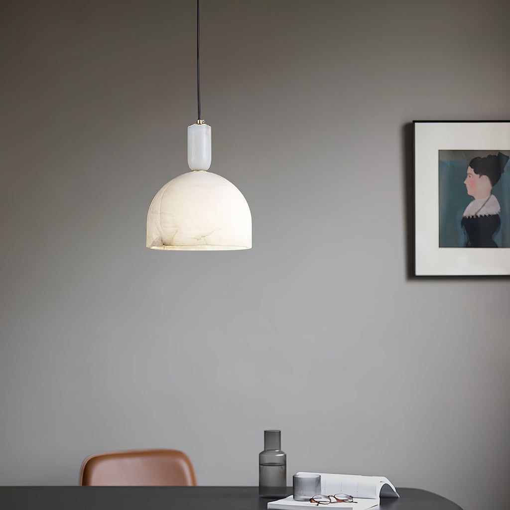 Clérachic Long-Drop Dome pendant light lit over a desk on a grey wall, a framed portrait hanging alongside.