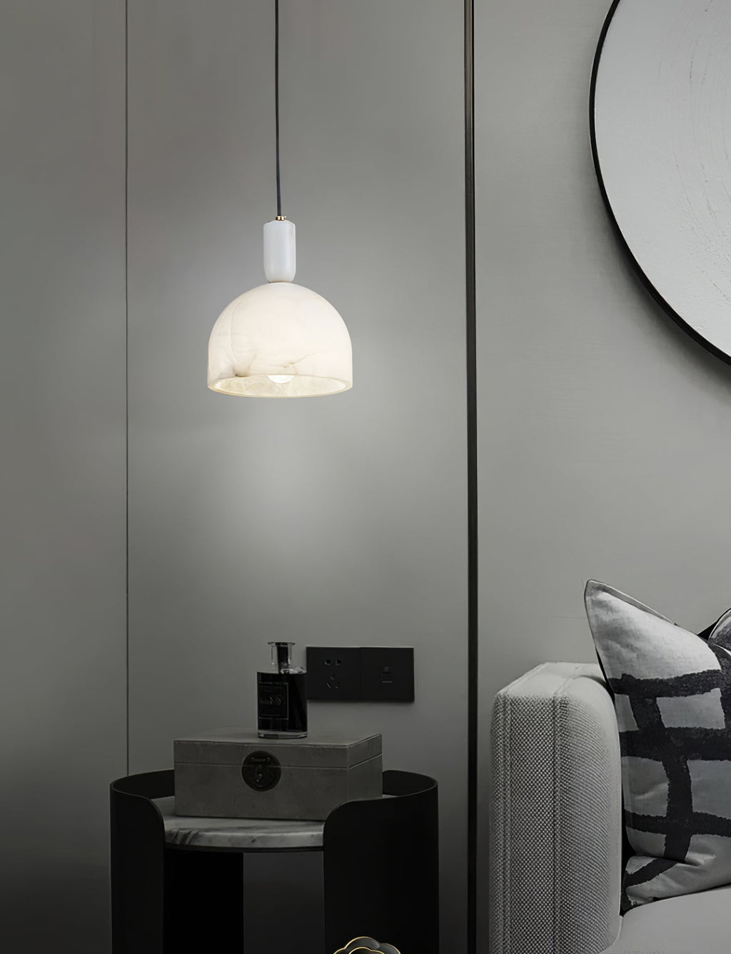 Clérachic Long-Drop Dome pendant light lit beside a black side table and a round mirror in a grey bedroom.