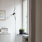A Clérachic black pendant spotlight hanging on a thin cable beside a bright window, with a potted herb and a small toaster below.