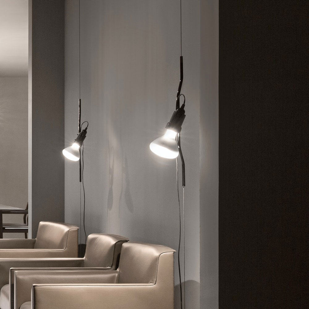 Two Clérachic spotlight pendants lit on long cables in a grey room, with leather armchairs below.