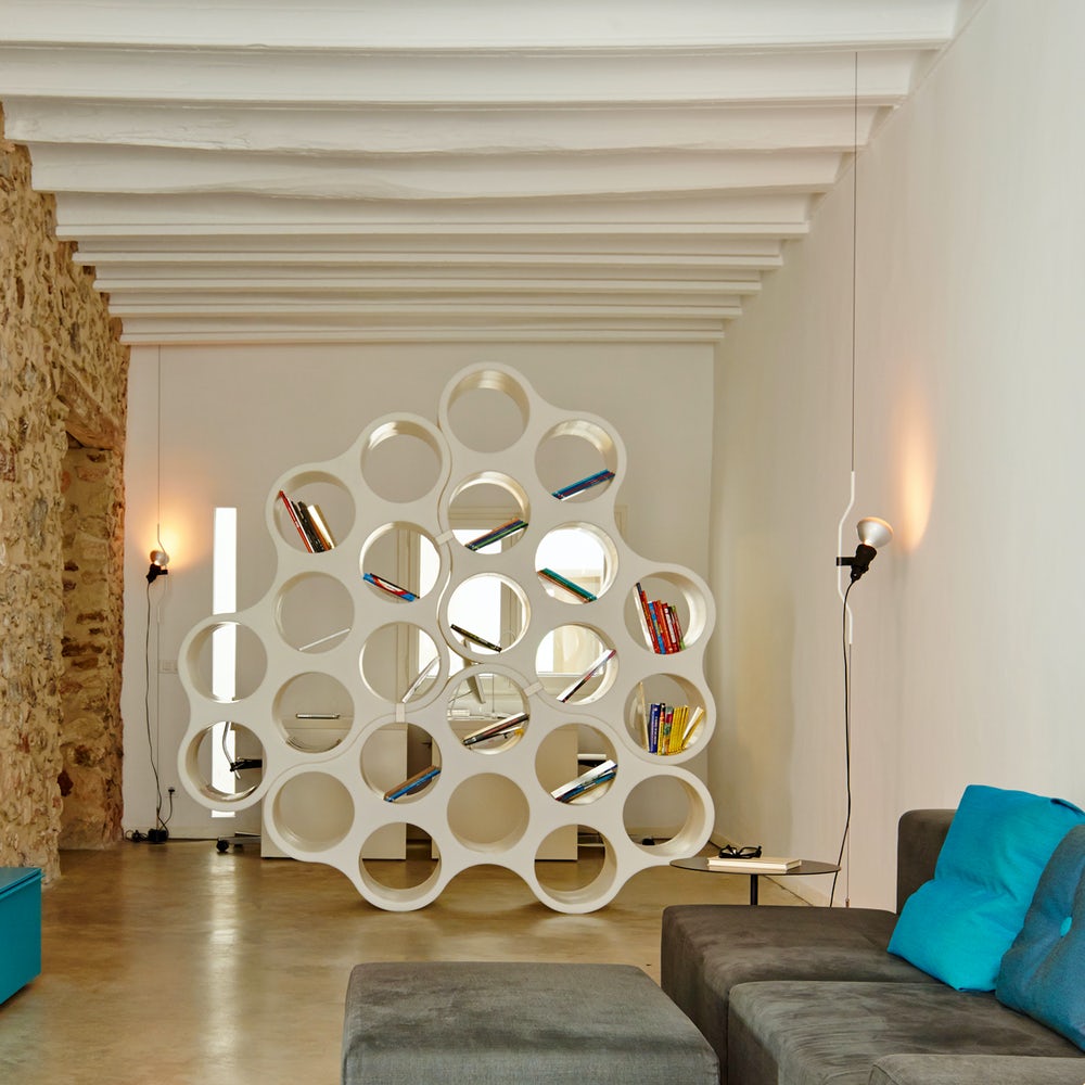 Two Clérachic pendant spotlights lit on thin cables in a loft room with a white cloud-shaped bookcase and a grey sofa.