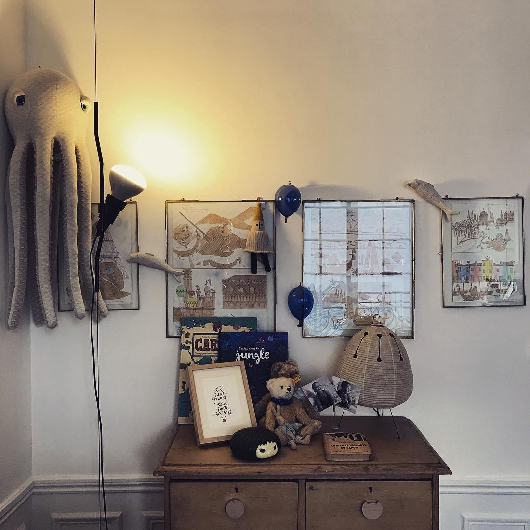 Lit Clérachic pendant spotlight on a cable beside a wooden chest, with framed pictures and a soft toy octopus on the wall.