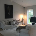 A Clérachic pendant spotlight lit in a living room with a white sofa, a glass table and a framed black and white portrait.