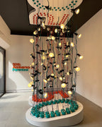 Installation of lit Clérachic spotlight pendants hanging in rows from the ceiling above a round white base with teal and red discs.