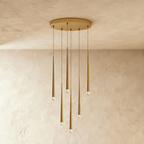 Clérachic six-light gold cone pendant cluster on an oval canopy, slender tapered tubes with crystal tips at varied heights.