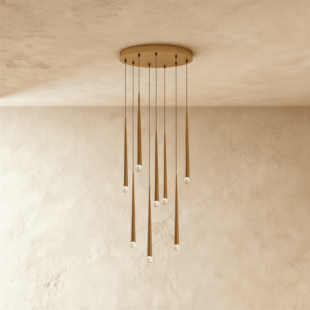 Clérachic eight-light gold cone pendant cluster on a round canopy, slim tapered tubes with crystal tips falling at staggered lengths.