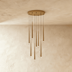Clérachic eight-light gold cone pendant cluster on a round canopy, slim tapered tubes with crystal tips falling at staggered lengths.