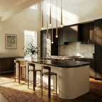 Clérachic six gold cone pendants with glowing crystal tips hung at staggered heights above a dark-topped kitchen island.