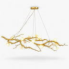 This Clérachic linear chandelier on a plain white background, with a long gold branch bearing white ceramic blossoms, hung from fine cords.